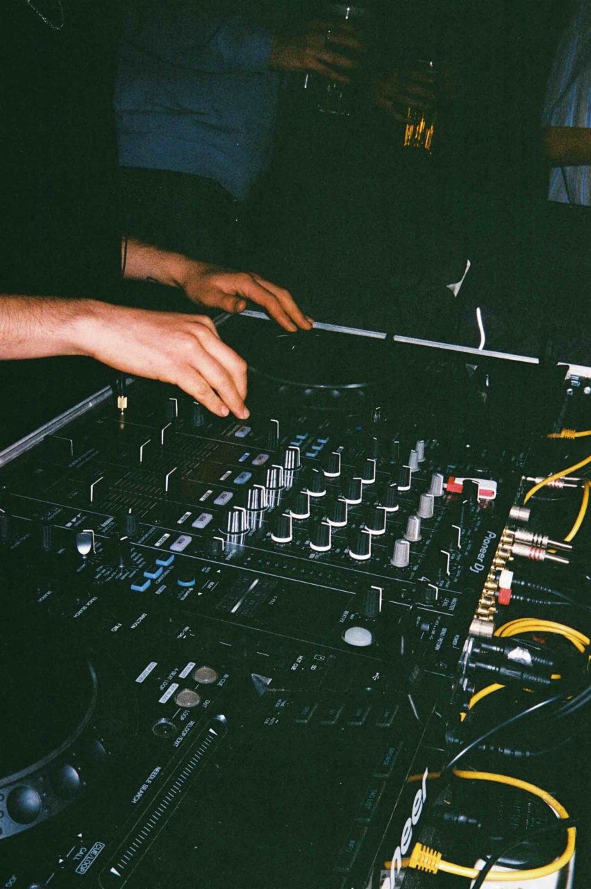 A close up photograph DJ using a mixing deck and turntables